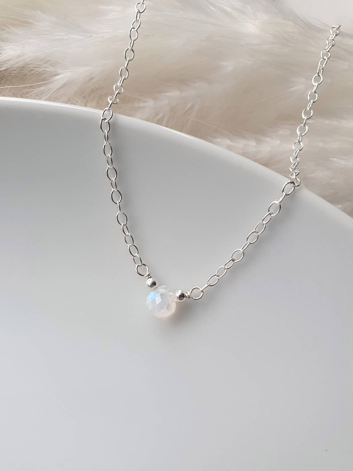 Silver necklace with a single pearl pendant on a white surface