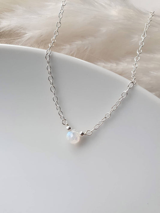 Silver necklace with a single pearl pendant on a white surface