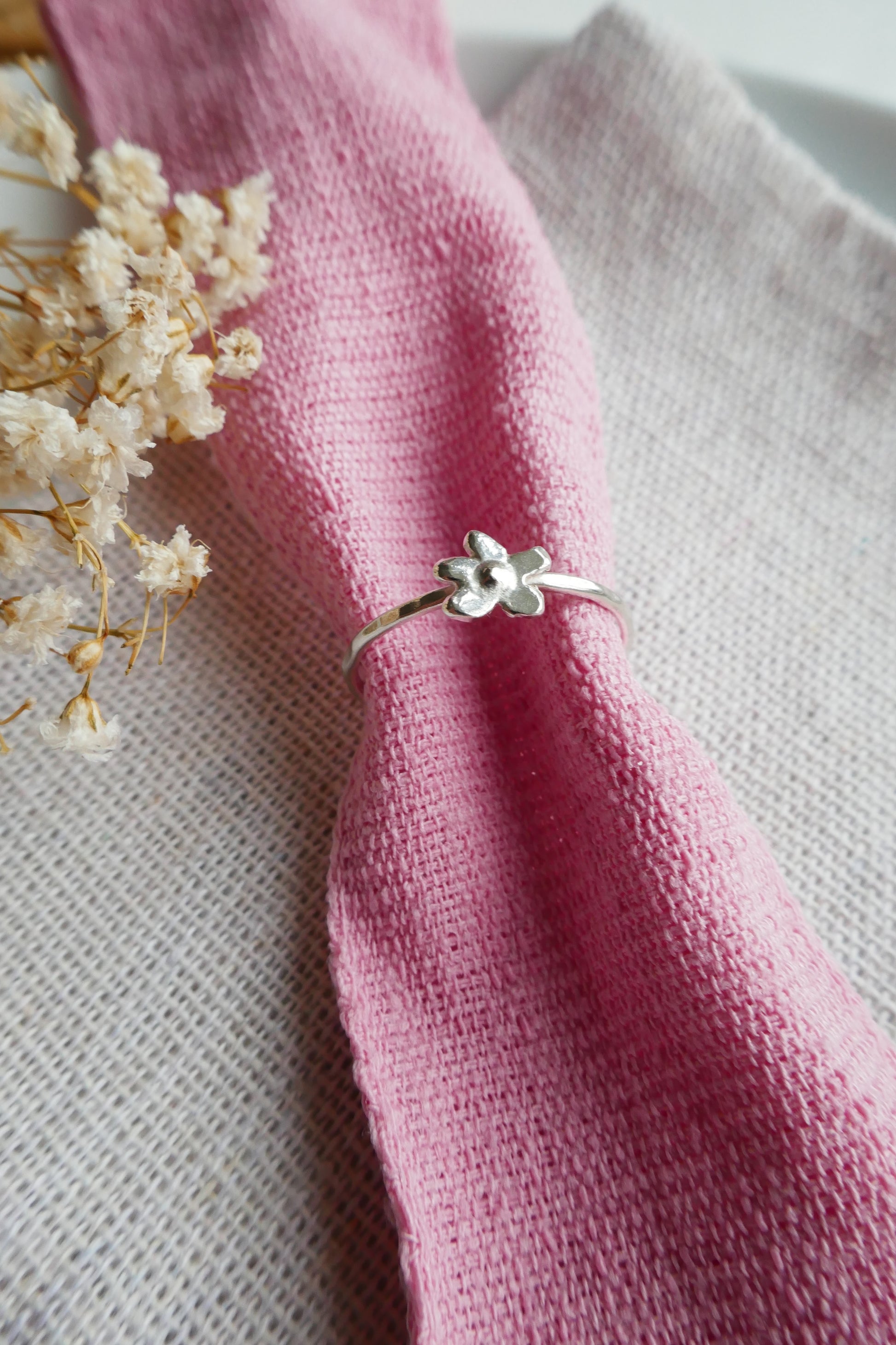 Silver ring with a floral design on a pink fabric background
