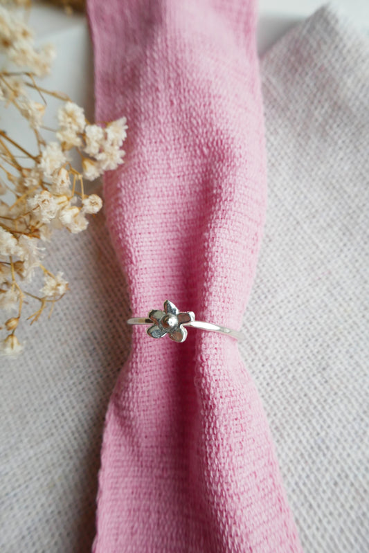 Silver ring with a floral design on a pink fabric background