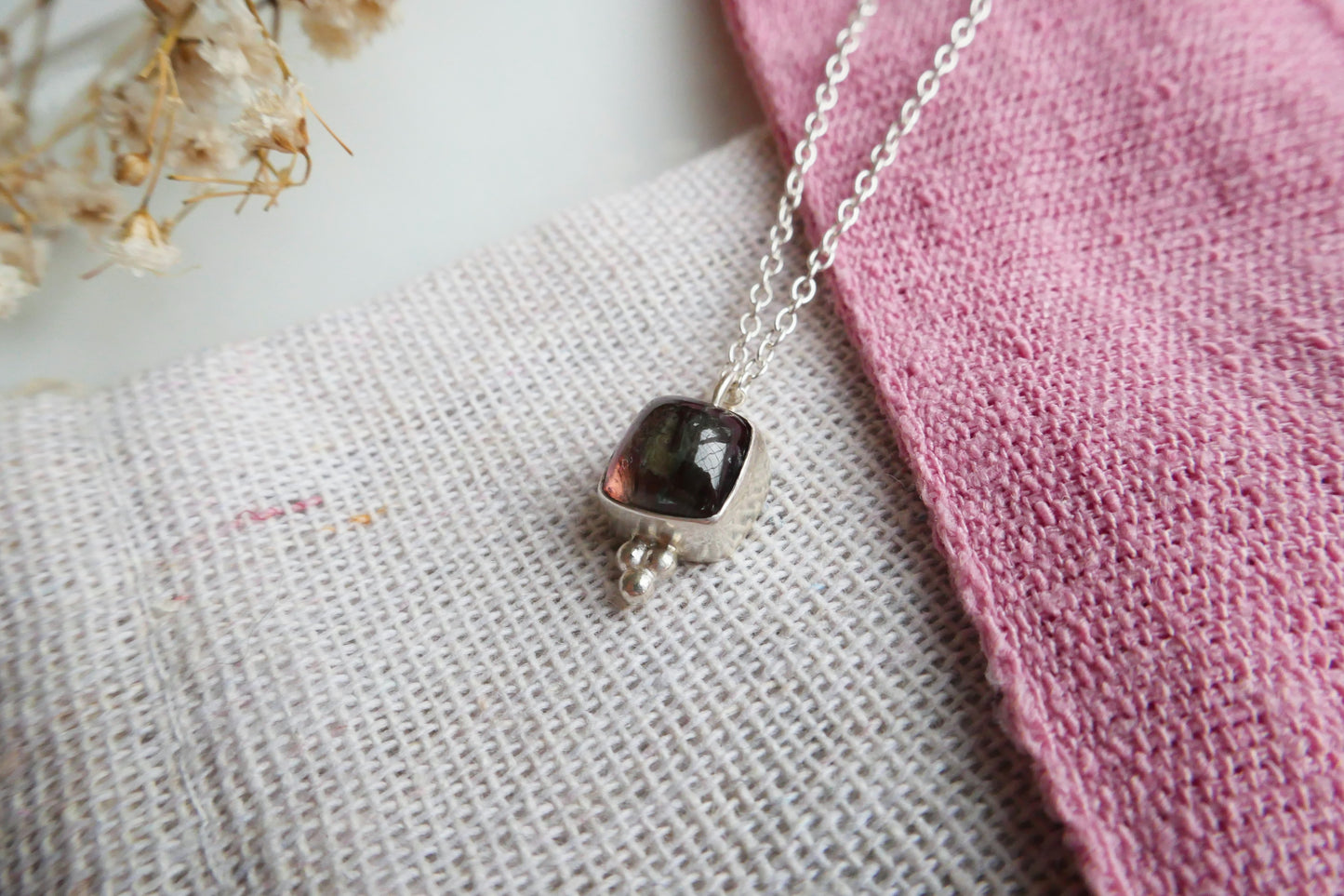 Necklace with a dark pendant on a textured fabric background