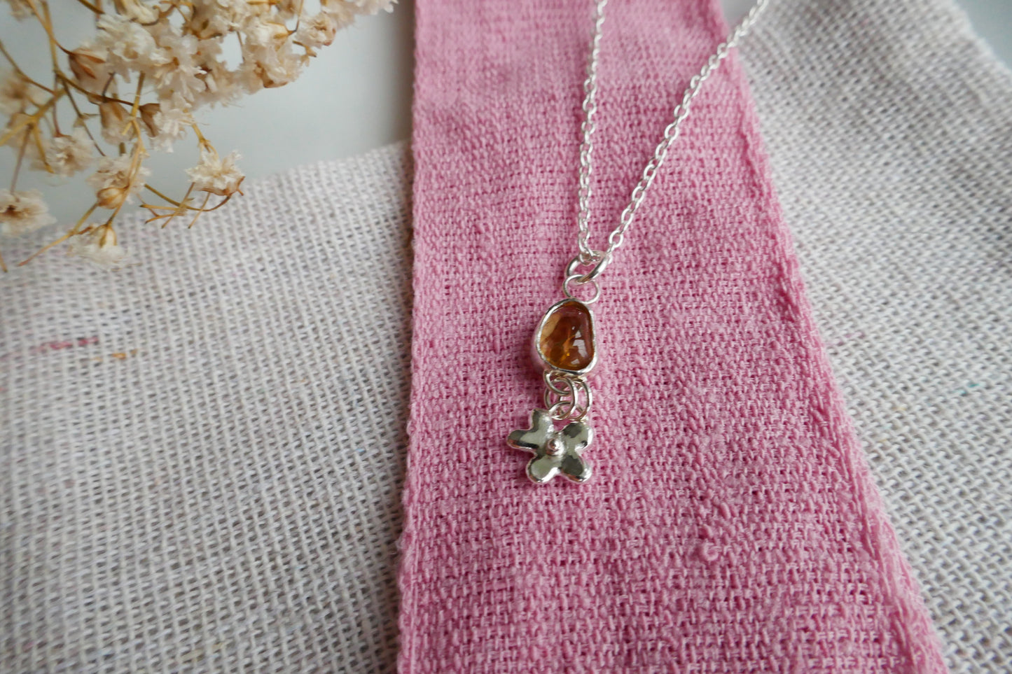 Silver necklace with a pendant on a pink fabric background