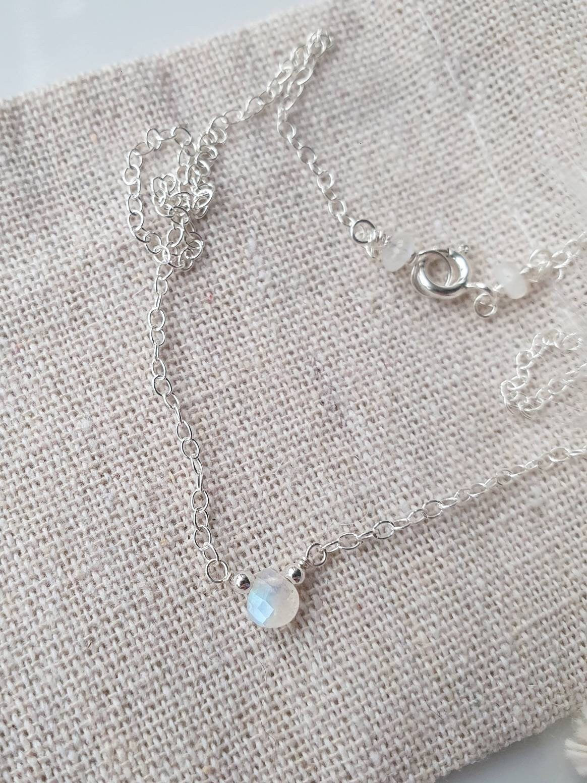 Silver necklace with a moonstone pendant on a light fabric background