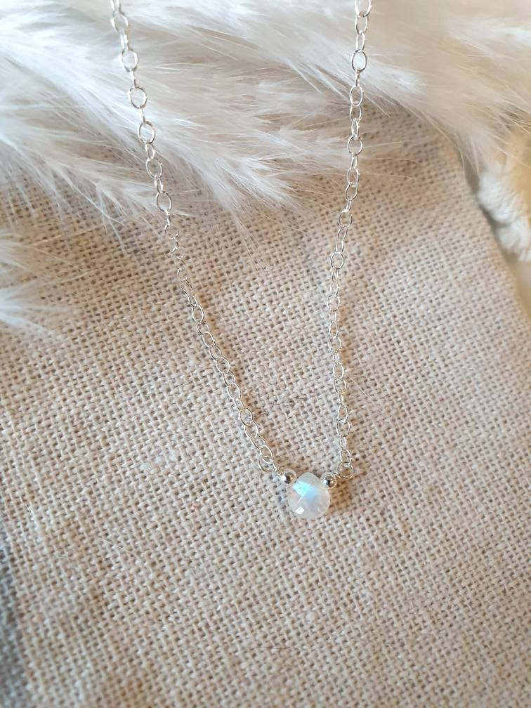 Delicate silver necklace with a small pendant on a textured fabric background