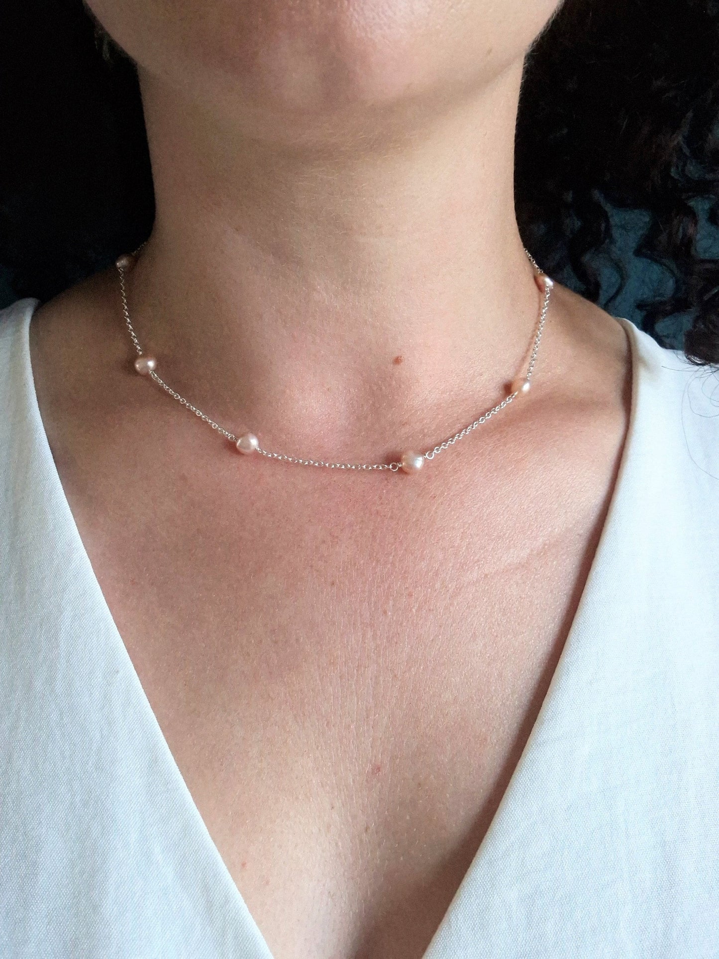 dainty freshwater pearl and sterling silver necklace.

A delicate sterling silver chain with small pink/ peach pearls stationed every couple of inches. The photograph shows a 16 inch necklace landing just below the collarbone.